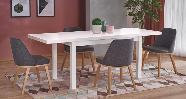 duży biały stół w stylu skandynawskim i komplet szarych tapicerowanych krzeseł w kuchni 